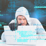 Un hombre con capucha y una computadora portátil